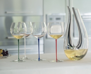 A RIEDEL Fatto A Mano Oaked Chardonnay glass in white filled with white wine on a white background. 