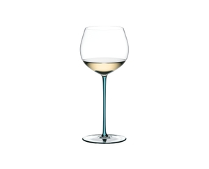 A RIEDEL Fatto A Mano Oaked Chardonnay glass in turquoise filled with white wine on a transparent background. 