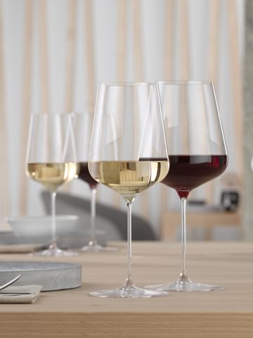 A SPIEGELAU Definition Bordeaux glass filled with red wine and a SPIEGELAU Definition white wine glass filled with white wine on a table. <br/>
