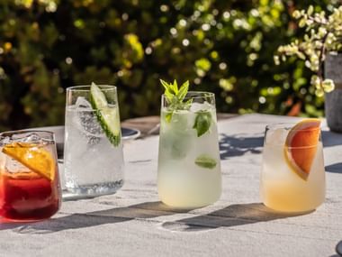 SPIEGELAU Capri Long Drink and Mixed Drinks glasses filled with colourful beverages on a white table top outdoors.