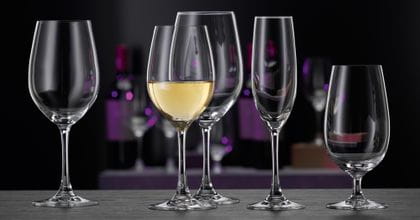 Die SPIEGELAU Winelovers Kristallglas-Kollektion, beginnend von links mit einem leeren Weißweinglas, einem gefüllten Weißweinglas, einem leeren Bordeauxglas, einem leeren Champagnerglas und einem leeren Bier- beziehungsweise Wasserglas.<br/>