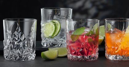 Vier NACHTMANN Sculpture Whiskey-Gläser auf einem Tisch, drei davon gefüllt mit verschiedenen alkoholischen und nicht-alkoholischen Getränken. Zwischen den Gläsern ist der Tisch mit Limettenscheiben dekoriert.<br/>