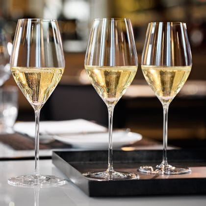 Mit Champagner gefüllte SPIEGELAU Highline Champagnergläser auf einem Serviertablett auf einem Tisch.<br/>