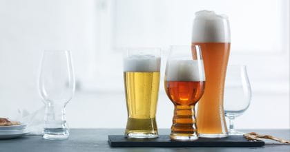 The Spiegelau Craft Beer IPA glass is positioned on the left of the image unfilled with the Spiegelau Beer Classics Tasting Set positioned on the right side of the image filled with their style-specific beer.