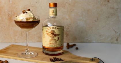 On the middle left of the image is a Spiegelau Lifestyle Coupette filled with a non-alcoholic affogatto. In the background on the left is a rose gold shot glass and in the background on the left is the non-alcoholic Lyre's Amaretti bottle.