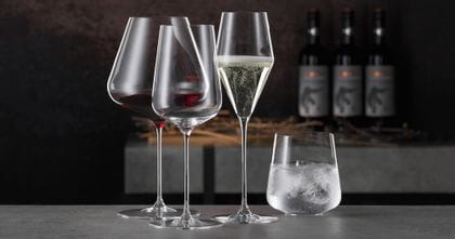 The SPIEGELAU Definition Burgundy glass filled with red wine, the filled Champagne glass, the empty white wine glass and the tumbler filled with water and ice cubes.<br/>