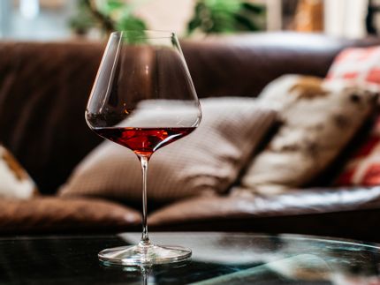 Spiegelau Definition Burgundy glass on a glass table filled with red wine with a couch in the background.