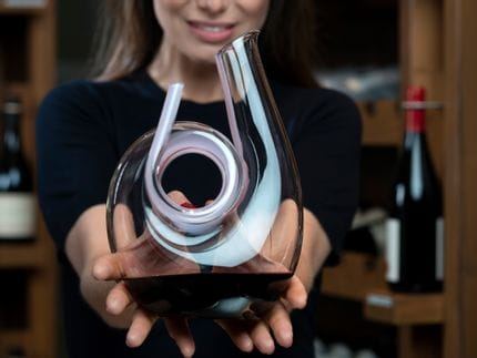 Lady holding the RIEDEL Curly Pink Mini Decanter filled with red wine.
