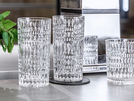 Two empty NACHTMANN Ethno longdrink glasses on a sideboard, left of them an Ethno tumbler with mint sprigs.<br/>
