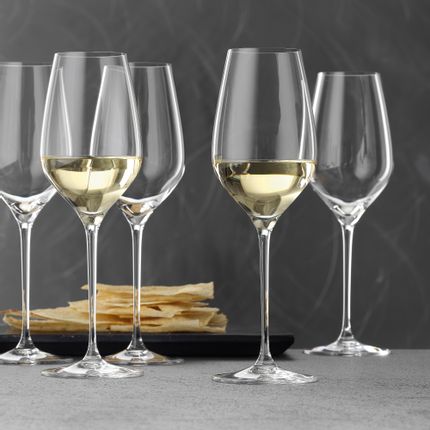 Verres à vin blanc SPIEGELAU Superiore, dont deux remplis de vin blanc. En arrière-plan, un plateau noir avec des chips.<br/>