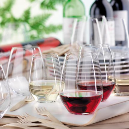 SPIEGELAU Authentis Bicchieri casual su un vassoio di servizio su un tavolo all'aperto. Due dei bicchieri senza stelo sono riempiti di vino rosso, uno di vino bianco. In primo piano ci sono forchette di legno e sullo sfondo una pila di piatti e altri bicchieri.<br/>