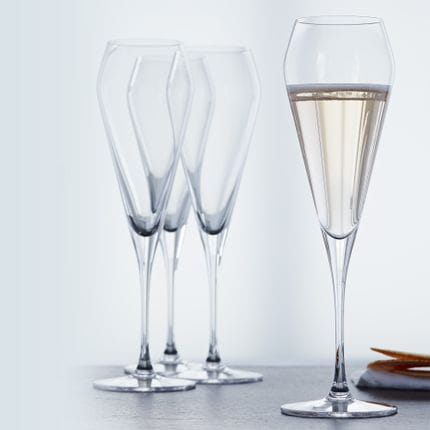 Cuatro copas de champán SPIEGELAU Willsberger Anniversary, una de ellas llena de champán.<br/>