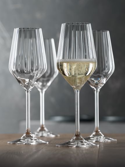 A group of SPIEGELAU Party Champagne glasses. Two of them filled with rosé Champagne, two with regular Champagne and two are empty. There is a cork on the table.<br/>