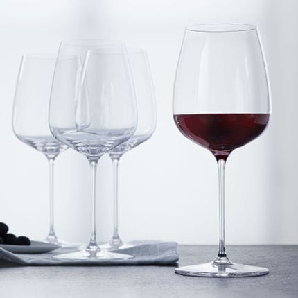 Quatre verres à Bordeaux SPIEGELAU Willsberger Anniversary, dont un rempli de vin rouge.<br/>