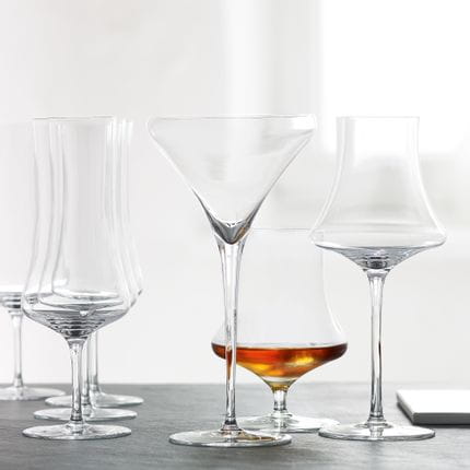 Le verre à martini et le verre à digestif SPIEGELAU Willsberger Anniversary vides et derrière eux le verre à whisky SPIEGELAU Willsberger Anniversary rempli.<br/>