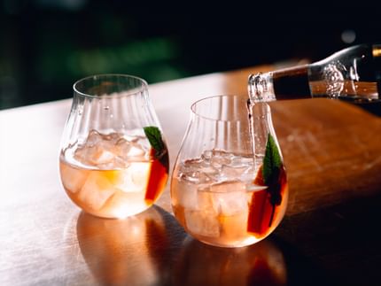 Two RIEDEL Gin Set Optical Glasses filled with a Gin & Tonic. A hand pours Fevertree Tonic into one of the glasses.