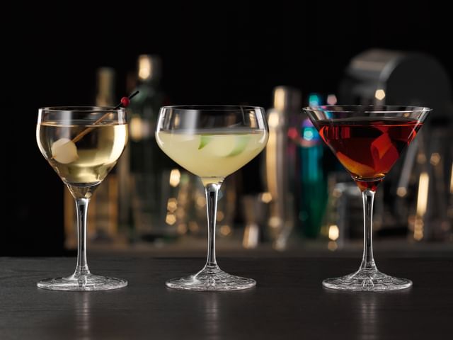 Les verres à cocktail de la collection Perfect Serve de SPIEGELAU, tous remplis de cocktails spécifiques. Le verre Perfect Nick and Nora se trouve à gauche, suivi du verre Perfect Coupette et du verre Perfect Cocktail à droite.<br/>