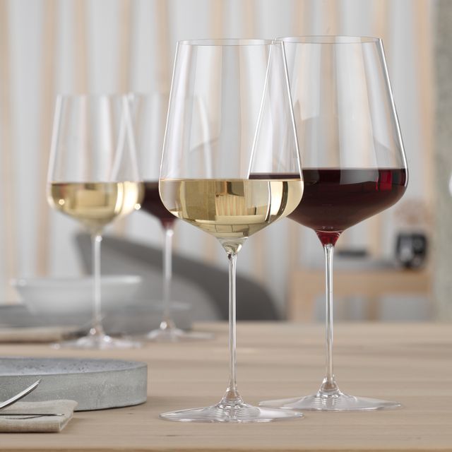 Un bicchiere SPIEGELAU Definition Bordeaux riempito di vino rosso e un bicchiere SPIEGELAU Definition da vino bianco riempito di vino bianco su un tavolo.<br/>
