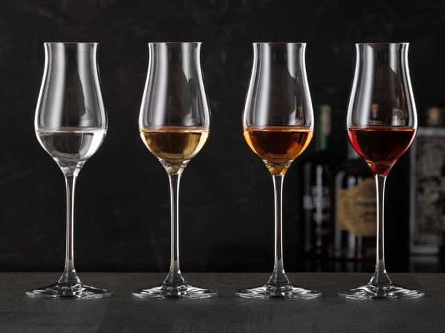 Vier SPIEGELAU Digestif-Gläser, gefüllt mit verschiedenen Spirituosen.<br/>