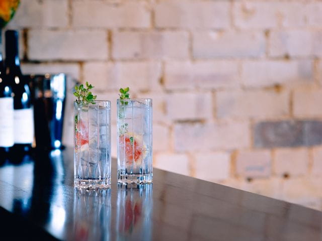 Two RIEDEL Drink Specific Glassware Highball glasses filled with G&T on a bar benchtop.