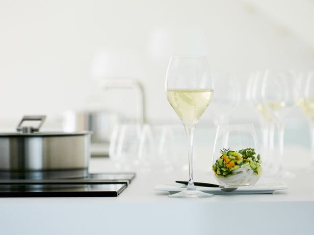Das mit Weißwein gefüllte SPIEGELAU Adina Prestige Weißweinglas neben einem SPIEGELAU Authentis Casual Becher gefüllt mit einem vegetarischen Nudelsalat.<br/>