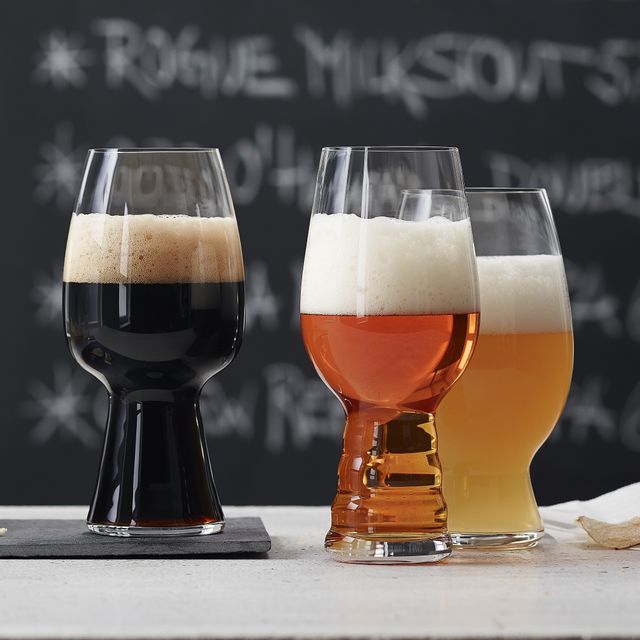 Three Spiegelau Craft Beer glasses filled on a white bench top with a black chalkboard in the background.
