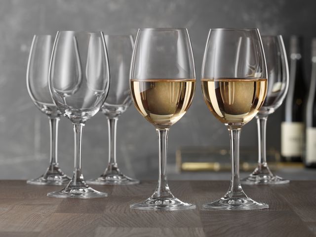 A group of SPIEGELAU Festival Tasting glasses on a table. In the foreground two of those glasses are filled with white wine.<br/>