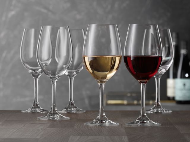 A group of SPIEGELAU Festival white wine glasses on a table. In the foreground one glass is filled with white wine and one glass with red wine, showing the universal use of these glasses.<br/>